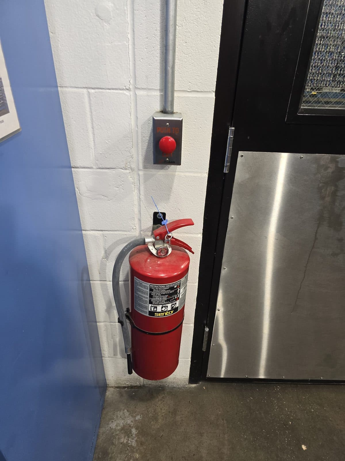 Fire extinguisher mounted beside a commercial egress door