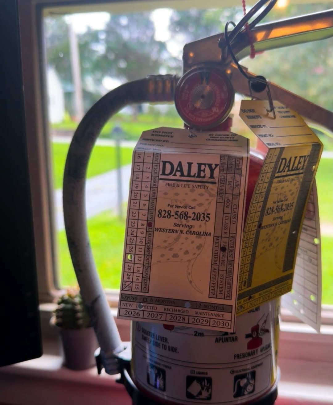Daley Fire & Life Safety inspection tag hanging on a serviced fire extinguisher