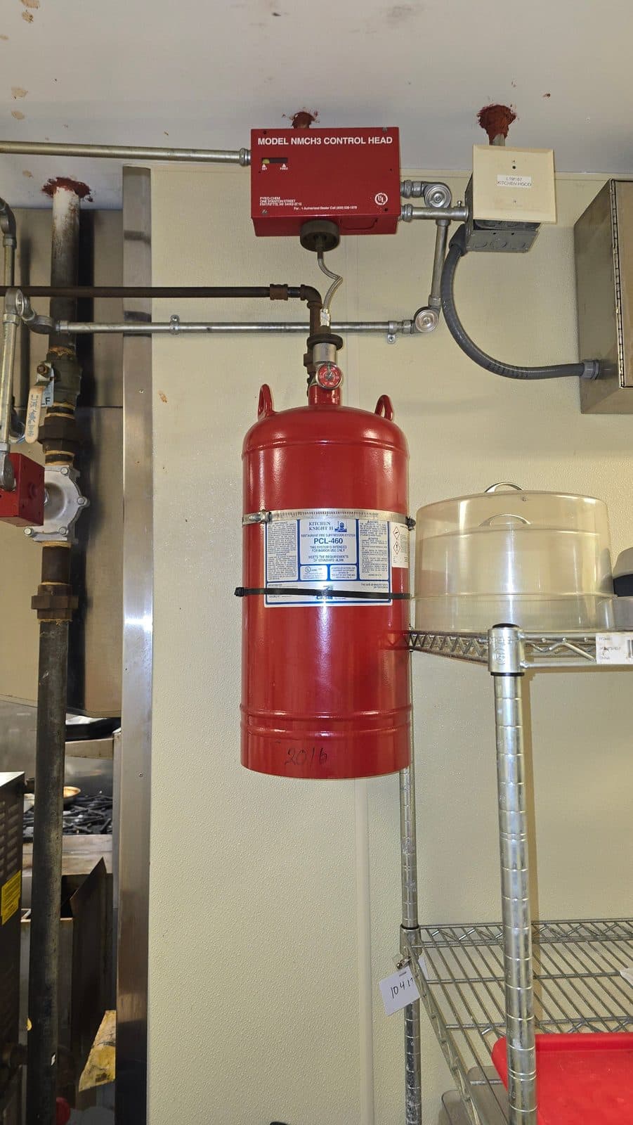 Commercial kitchen wet chemical fire suppression system above a cook line